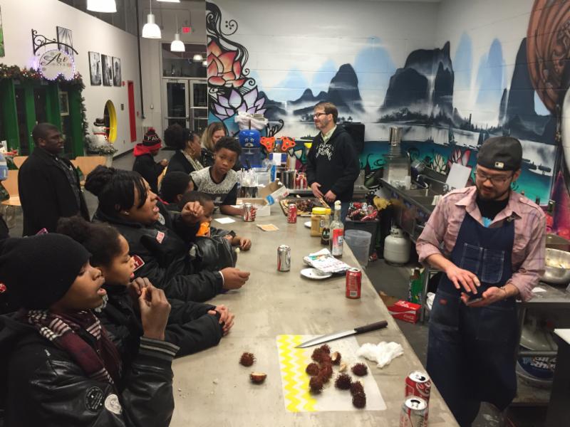 Photo of children watching a man prepare food